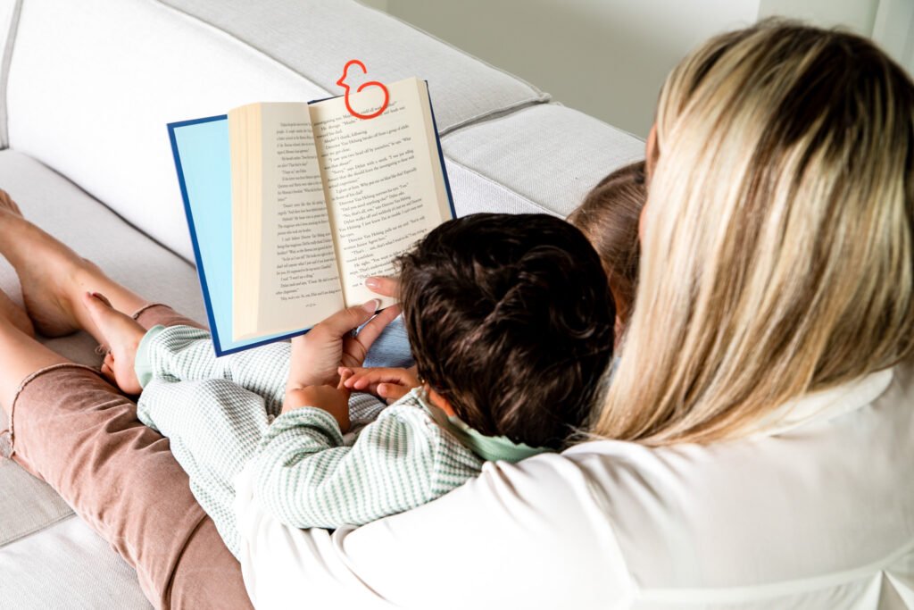 Mom and toddlers reading a physical book together using Duck-links bookmark