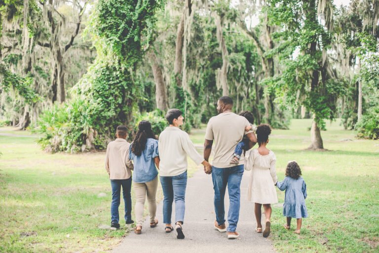 Family of 7 and owners of Giplings walk together holding hands with Oaks trees