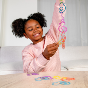 Cute black girl with pig tails smiling linking together colorful duck-links