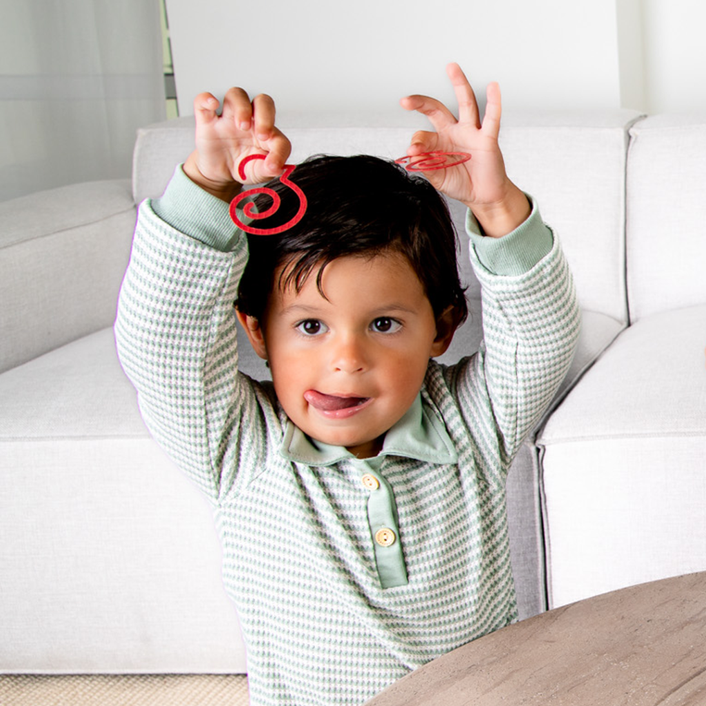 Cute boy with his tongue out plays with Duck-links bookmarks at table