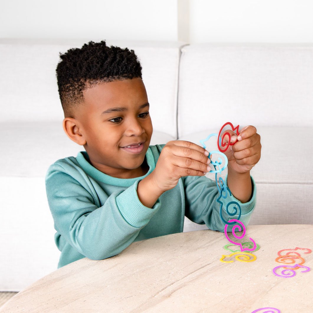 5 year old boy plays with Duck-links linking them together to improve fine motor skills
